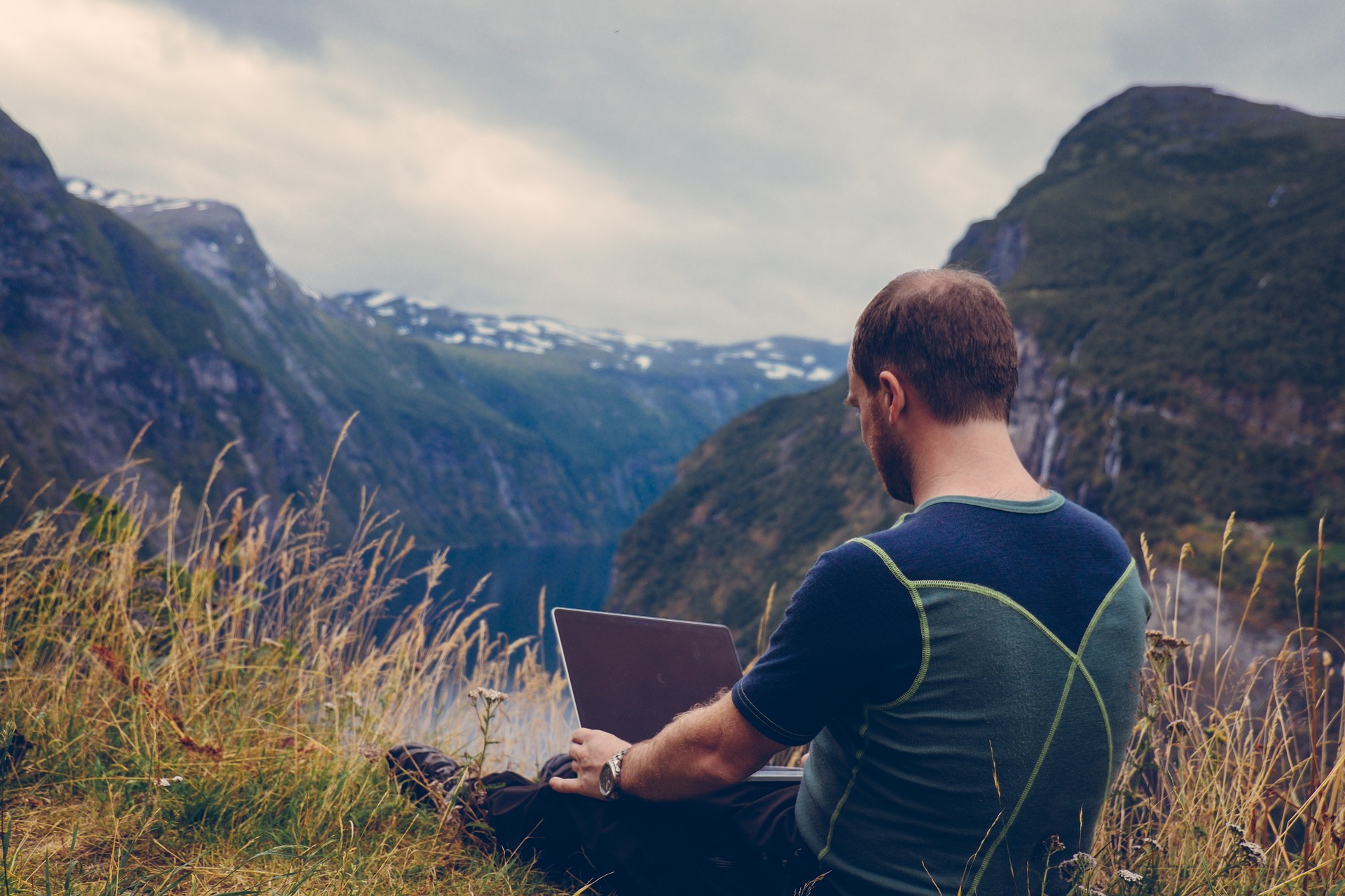 Mann mit Laptop auf Berggipfel