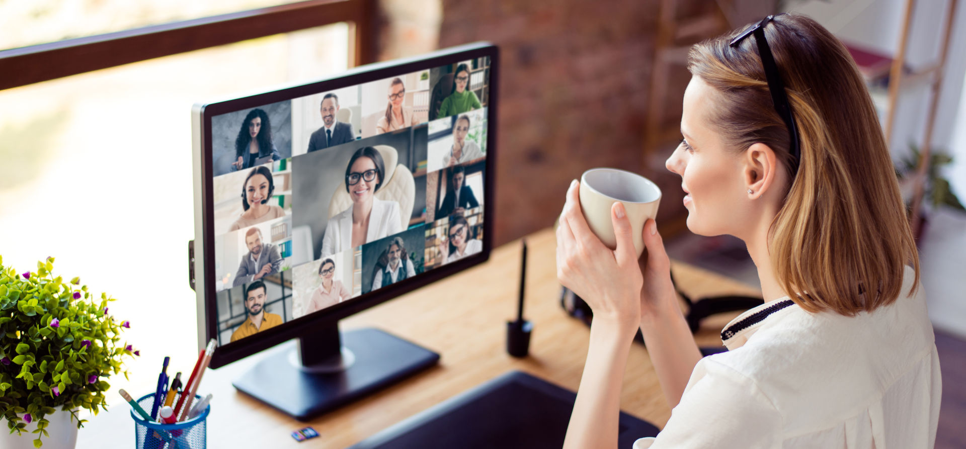 Frau vor Bildschirm, auf dem eine Videokonferenz läuft